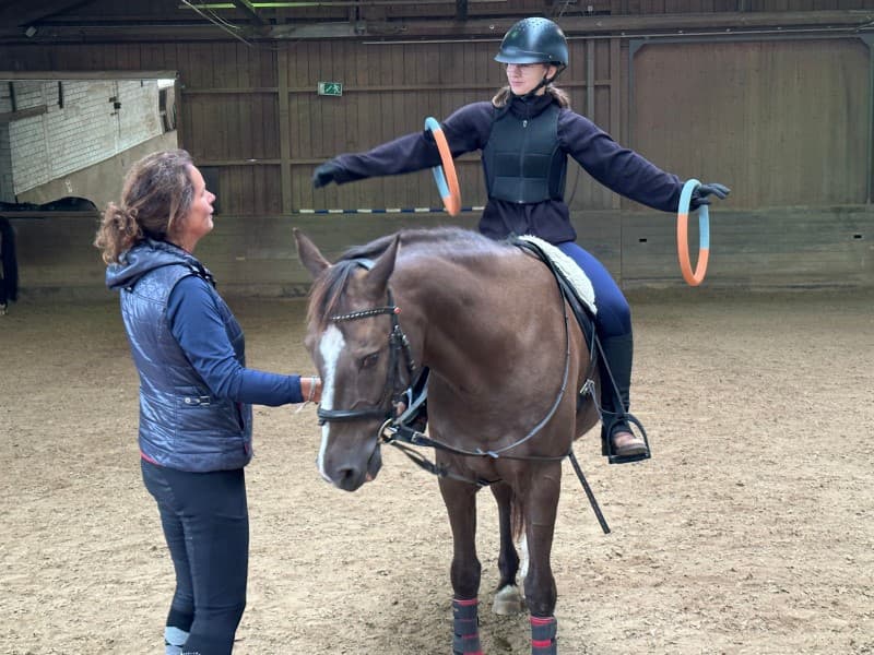 Therapeutsiches Reiten - Person balanciert Ringe auf Pferd