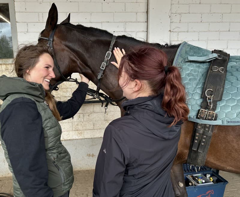 Therapeutsiches Reiten - zwei Frauen streicheln Pferd am Hals